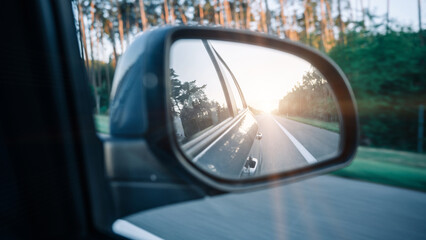 Road sunset car mirror. Summer sun, highway car road reflection in mirror. Vacation trip concept.