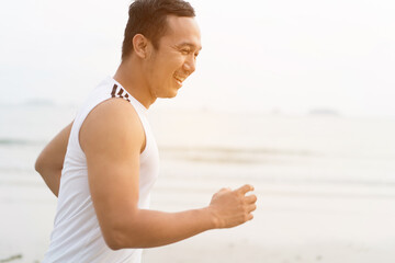 Fototapeta na wymiar asian sport man running along seaside. running on beach with healthy toned legs body, Hamstring muscles, knee joint health active lifestyle panoramic banner background. the beach runners working out