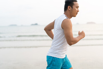 Fototapeta premium asian sport man running along seaside. running on beach with healthy toned legs body, Hamstring muscles, knee joint health active lifestyle panoramic banner background. the beach runners working out