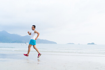 asian sport man running along seaside. running on beach with healthy toned legs body, Hamstring muscles, knee joint health active lifestyle panoramic banner background. the beach runners working out