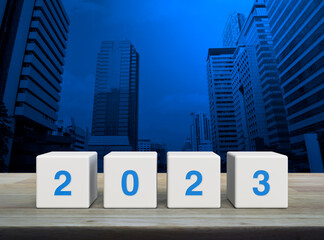 2023 letter on white block cubes on wooden table over modern office city tower and skyscraper,...
