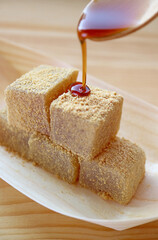 Mouthwatering Japanese Traditional Confection Called Warabimochi Being Poured on Top with Kuromitsu syrup