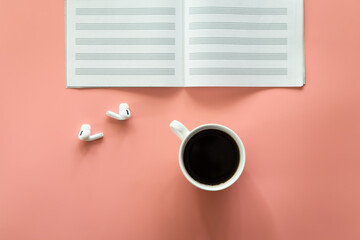 Minimalistic pink background with a cup of coffee, notepad, flat lay.