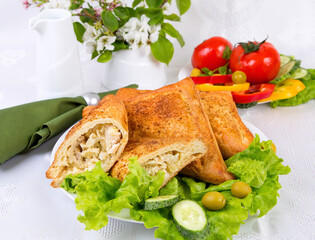 puff pastries stuffed with chicken meat, on a white dish with vegetables on a light background