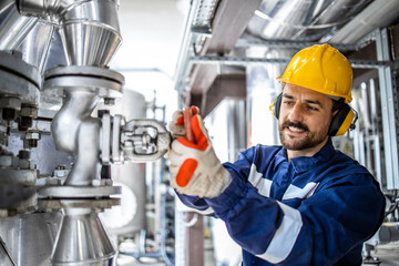 Caucasian smiling man working in heating plant adjusting water pressure and temperature in boiler...
