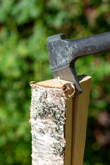 Birch log with an axe inside the the firewood. Image taken outdoors on a sunny day. Cold climate and warming up the house with firewood concept image.