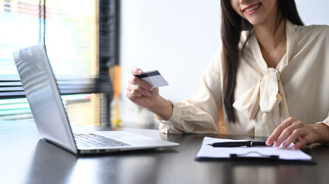 Cropped view of smiling young woman holding credit card and using laptop. Online shopping, e-commerce concept