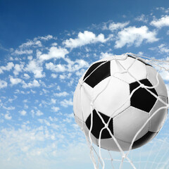 Naklejka premium Soccer ball in net against blue sky