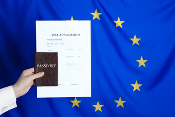 Woman holding visa application form and passport against European Union flag, closeup. Space for...