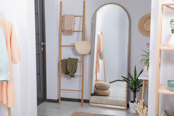 Hallway interior with wooden ladder and floor mirror