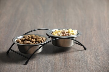 Bowls with dry dog food on wooden floor indoors