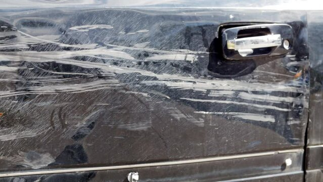 Damaged car after an accident. Repair of dents and scratches on the car body after an incident at a service station. Scratch on the front left driver's door in black. Car service concept. Side doors.