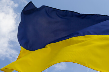 Ukrainian flag in the wind on blue sky background. Large national yellow blue flag of Ukraine. Big Ukrainian state banner