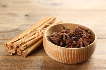 Aromatic cinnamon sticks and anise in bowl on wooden table