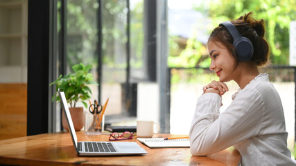 Young businesswoman making video call to business partner or watching online webinar on her laptop