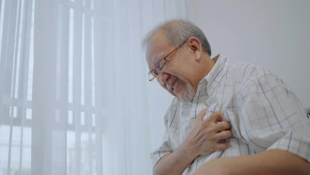 Asian senior man suffering from heart attack. Male patient on wheelchair has difficulty breath and having chest pain.
