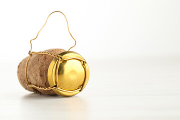 Cork of sparkling wine and muselet cap on white wooden table, closeup. Space for text