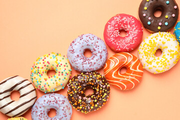 Delicious glazed donuts on orange background, flat lay