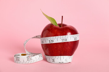 Fresh red apple with measuring tape on pink background