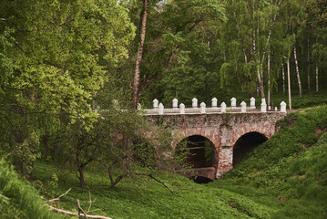 An old bridge with white pillars among green trees.