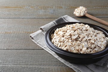 Bowl of oatmeal and spoon on wooden table. Space for text