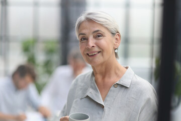 close-up mature woman holding a cup in the office