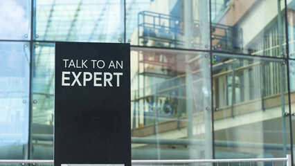 Talk to an expert on a city-center sign in front of a modern office building	
