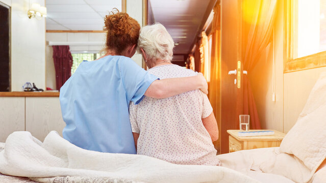 Nurse in hospice hugs elderly woman for comfort