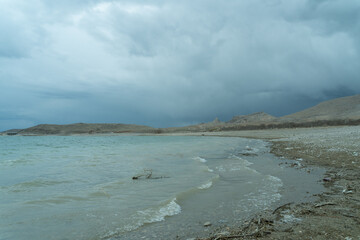 Wavy lake shore and cloudy sky.