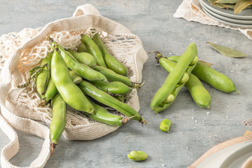 Fresh and raw green broad beans on kitchen table.