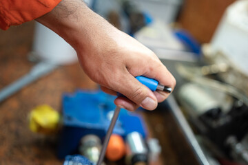 Action of a worker is using hexagonal spanner to tightening the screw of an electronic equipment during repairing. Industrial working scene photo, close-up and selective focus at hand.