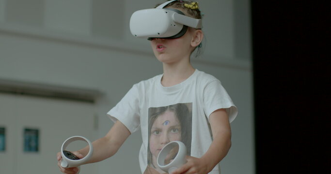 A smart schoolboy uses digital VR glasses and controllers in his hands to create a 3d reality. It focuses on movement. Image formation and output in virtual reality systems.