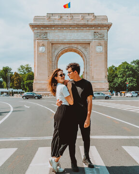 Young traveling couple embracing each other near Triumphal arch