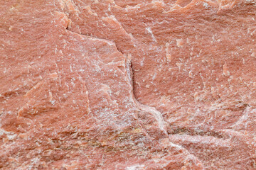 Texture of a stone wall with cracks and scratches which can be used as a backgr. Texture of red stone.