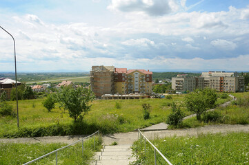 Fototapeta na wymiar Lawn, trees, buildings under construction, blue sky. Outskirts of Uzhgorod, Ukraine