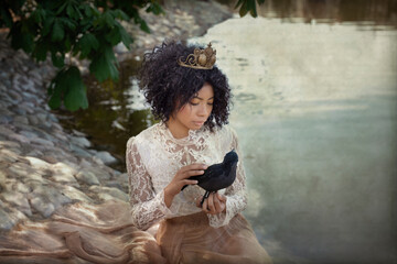Calm ethnic woman stroking crow near pond