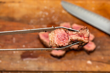 barbecue tong picking up sliced meat