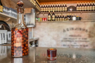 Bottle and shot glass with a traditional cherry liqueur Ginjinha close-up in Lisbon, Portugal. - 523770333