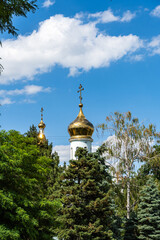 Fototapeta na wymiar Temple of Kazan Icon of Mother of God. Golden domes with orthodox crosses against background of blue sky. Close-up. Russian Orthodox Church, Ekaterinodar diocese. Krasnodar, Russia - June 16, 2022