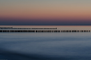 Sonnenuntergang an der Ostsee mit Buhnen als Küstenschutz. Buhnen werden auch als Kribbe, Stack, Schlenge oder Höft bezeichnet.