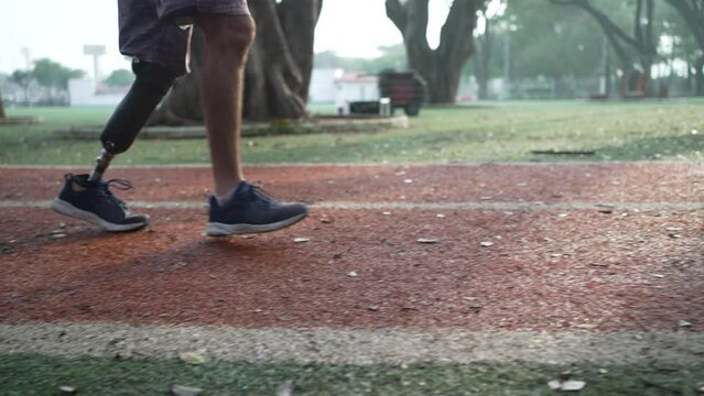 An athletic disabled man with prosthetic leg running on racing runner track in the morning