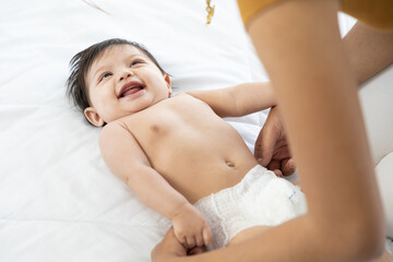 mother changing diaper a newborn baby lying on the bed