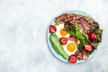 Ketogenic diet food, Fried egg bacon with avocado, strawberries and fresh salad on a light background. healthy meal concept, Long banner format. top view