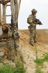 2 Army military soldier in the battle field sitting knee down on the ground hold the gun alert look...