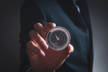 businessman holds a metal compass in his hands.