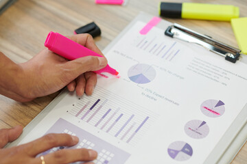 Hands of manager highlighing important figures in report with bright pink color