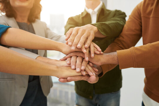 Closeup image of business colleagues stacking hands to encourage team spirit