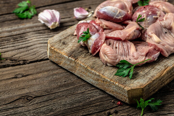 Raw uncooked chicken gizzards, stomach on a wooden background. Traditional Korean spicy chicken meat. Long banner format. top view