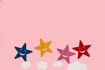 colorful stars on clouds at bottom of pink background, copy space above, creative art design