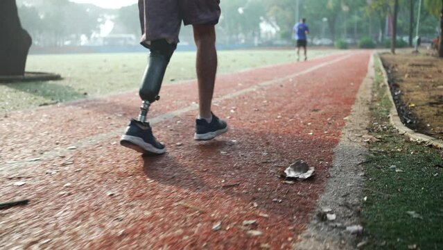 Determined disabled athlete running outside with prosthetic leg. Motivational amputee on runner track